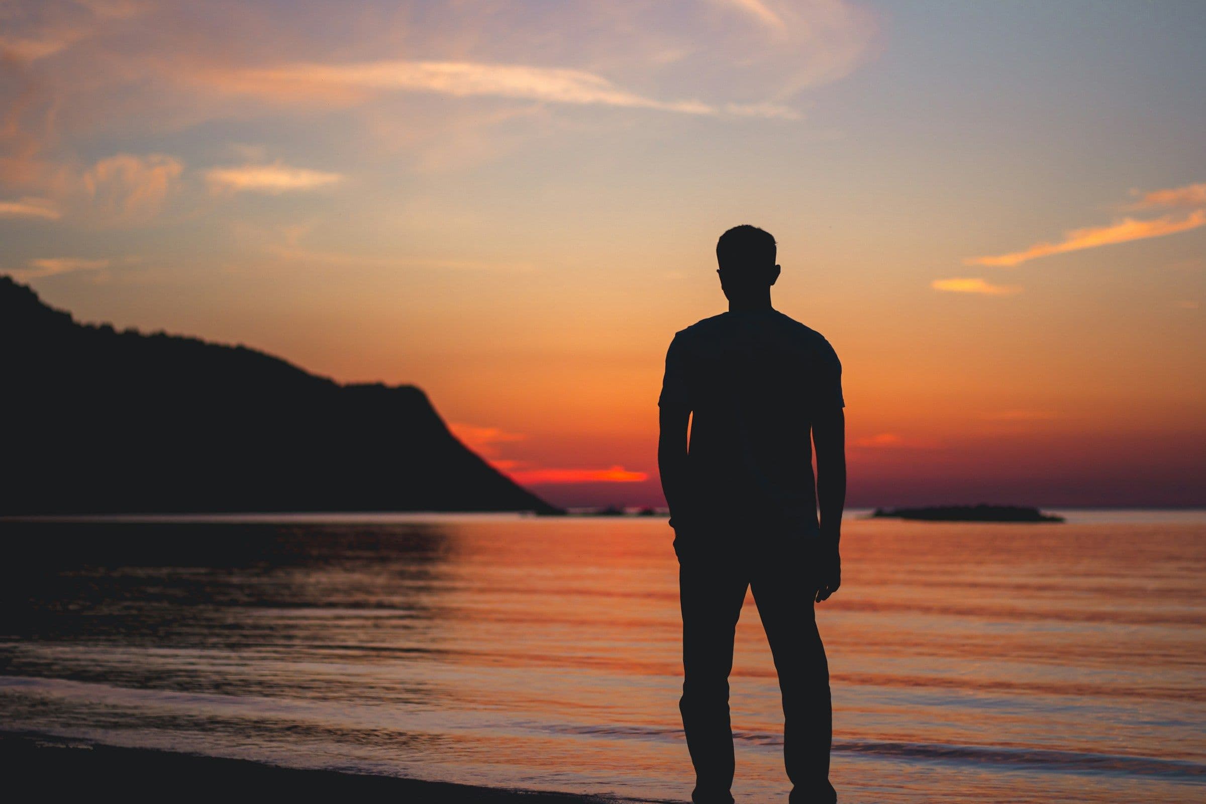 Man standing in reflection by the sea